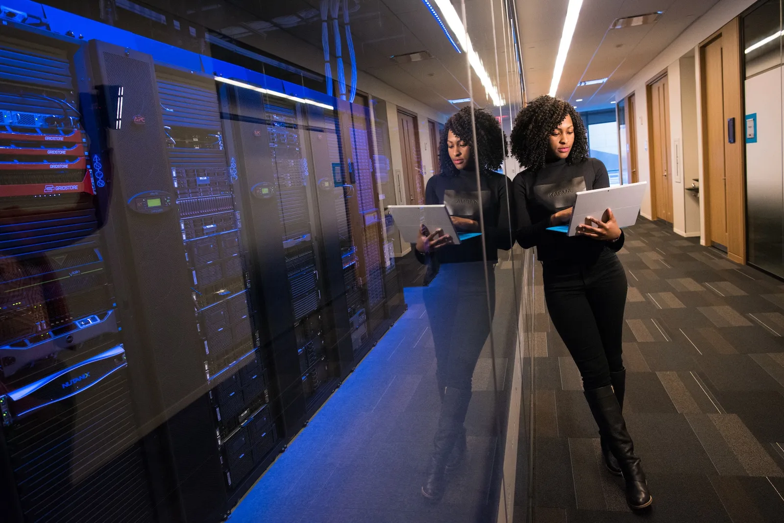 Une collaboratrice consulte une tablette dans un couloir de salle serveurs